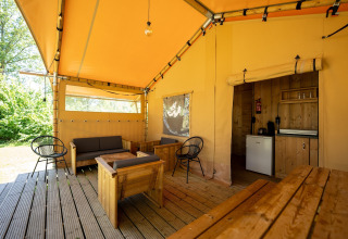 Tente safari au Holiday park Hunzedal 16 aux Pays-Bas, avec meubles en bois et espace détente.