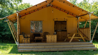 Safari tent at Holiday park Hunzedal 16 featuring a wooden deck, outdoor seating, and a picnic table.
