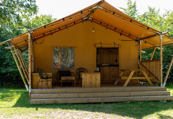 Safari telt ved Holiday park Hunzedal 16 med træterrasse, siddepladser og picnicbord omgivet af natur.