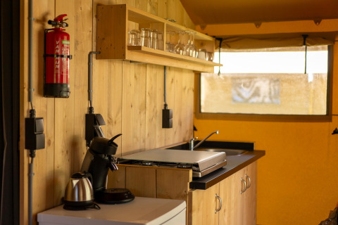 Binnenkant safaritent bij Holiday park ‘Hunzedal 16’ in Nederland met compacte houten keuken.