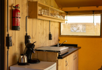 Binnenkant safaritent bij Holiday park ‘Hunzedal 16’ in Nederland met compacte houten keuken.
