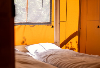 Binnenkant van een safaritent met zonlicht op twee bedden in Holiday park «Hunzedal 16», Nederland.