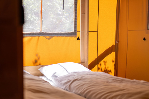 Indersiden af et safaritelt med sollys, der falder på to senge i Holiday park «Hunzedal 16», Holland.