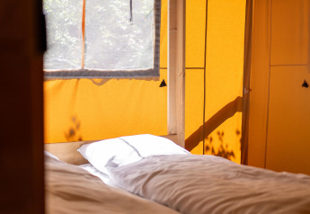 Interior de una tienda safari con luz solar sobre dos camas en Holiday park «Hunzedal 16», Países Bajos.