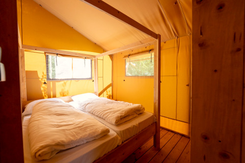 Interieur van een gezellige safaritent met tweepersoonsbed in vakantiepark Hunzedal 16 in Nederland.