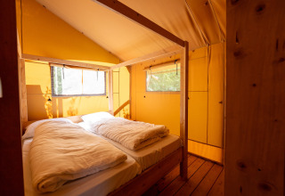 Interno di una confortevole tenda safari con letto matrimoniale presso Holiday park Hunzedal 16 nei Paesi Bassi.