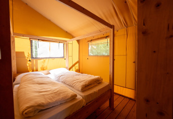 Interior de una acogedora tienda safari con cama doble en el parque vacacional Hunzedal 16 en los Países Bajos.