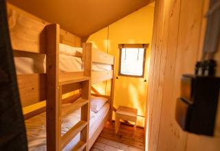 Interieur van een safaritent met houten stapelbedden in Holiday park Hunzedal 16 in Nederland.