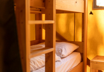 Knusse kamer met houten stapelbed in een safaritent op vakantiepark Hunzedal 16 in Nederland.