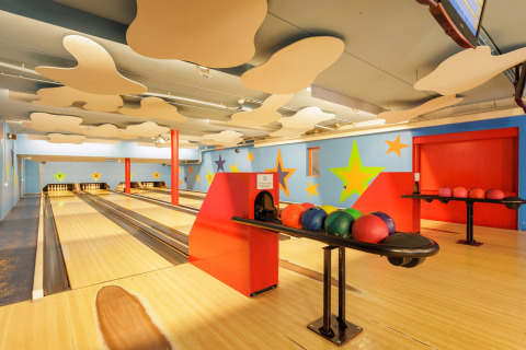 Indendørs bowlingbane med farverige vægge, stjerner og bowlingkugler på Holiday park Hunzedal 16, Holland.