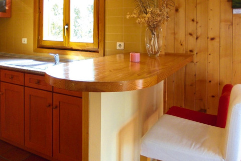Houten keuken met barblad en wit-rode stoel bij Holiday homes Quinta dos Curubás in Portugal.