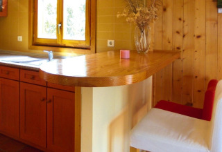 Houten keuken met barblad en wit-rode stoel bij Holiday homes Quinta dos Curubás in Portugal.