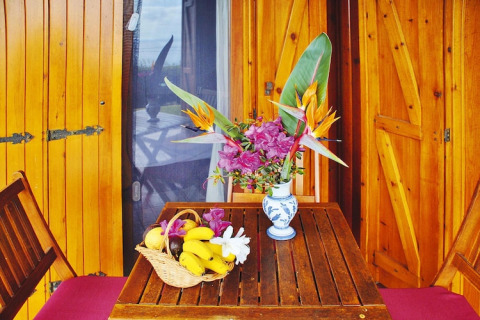 Houten tafel met bloemenvaas en fruitmand op het terras van Holiday homes Quinta dos Curubás in Portugal.