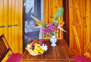 Houten tafel met bloemenvaas en fruitmand op het terras van Holiday homes Quinta dos Curubás in Portugal.