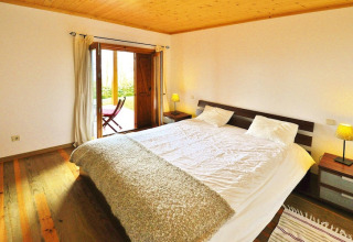 Slaapkamer in Holiday Homes Quinta dos Curubás, Portugal, met tweepersoonsbed, hout en balkon.