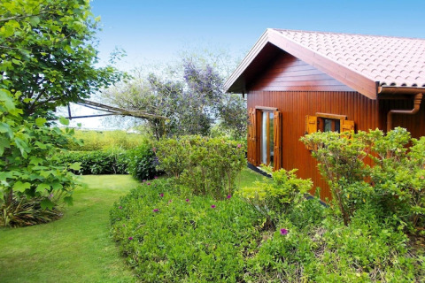 Houten bungalow met pannendak omringd door tuin en groen bij Quinta dos Curubás, Portugal.