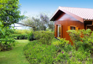 Houten bungalow met pannendak omringd door tuin en groen bij Quinta dos Curubás, Portugal.