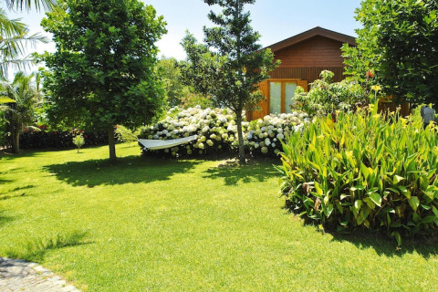 Knus bungalow en groene tuin bij Quinta dos Curubás, Vila Franca do Campo, Portugal, onder blauwe lucht.