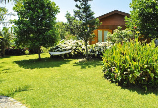 Knus bungalow en groene tuin bij Quinta dos Curubás, Vila Franca do Campo, Portugal, onder blauwe lucht.