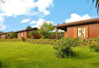 Foto van houten bungalows met groene tuinen en blauwe lucht bij Quinta dos Curubás, Vila Franca do Campo, Portugal.