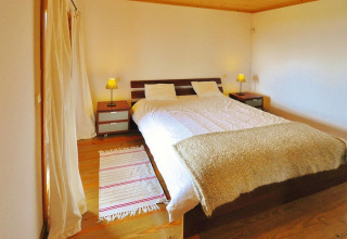 Lichte slaapkamer met tweepersoonsbed, nachtkastjes, lampen en houten vloer in Quinta dos Curubás, Portugal.