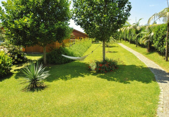 Giardino curato con amaca tra gli alberi e prato soleggiato presso Holiday homes Quinta dos Curubás, Portogallo.