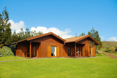 Houten bungalow bij Holiday homes Quinta dos Curubás, Vila Franca do Campo, Portugal, met groene grasmat.