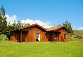 Houten bungalow bij Holiday homes Quinta dos Curubás, Vila Franca do Campo, Portugal, met groene grasmat.