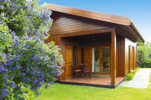 Houten bungalow met veranda en tuinmeubilair bij Holiday homes Quinta dos Curubás, Portugal, omringd door groen.