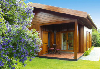 Houten bungalow met veranda en tuinmeubilair bij Holiday homes Quinta dos Curubás, Portugal, omringd door groen.