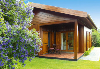Bungalow in legno a Holiday homes Quinta dos Curubás, Portogallo, con veranda e giardino fiorito.