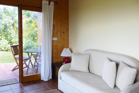 Lichte bungalow woonkamer met bank, kussens, lamp en schuifdeur naar terras met tuinmeubels in Portugal.