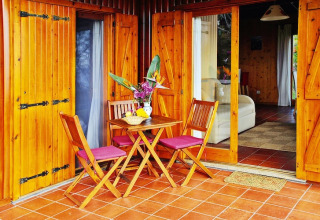 Houten terras met tafel en stoelen voor bungalow bij Quinta dos Curubás, Vila Franca do Campo, Portugal.