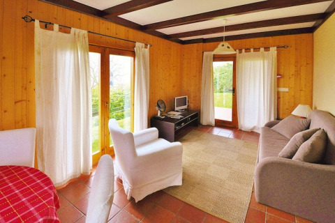 Lichte woonkamer in een vakantiehuis met houten wanden, grote ramen en knusse inrichting in Portugal.