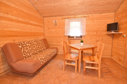 Gezellige houten leefruimte met sofa, eettafel, vier stoelen en tv bij Cottages ranch by the sea, Denemarken.