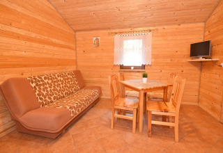 Soggiorno accogliente in legno con divano, tavolo da pranzo e TV in Cottages ranch by the sea, Danimarca.