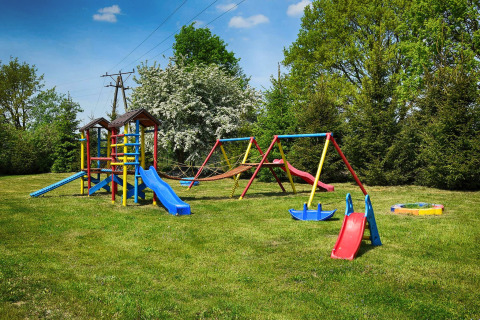 Spielplatz mit Rutschen und Schaukeln auf einer Wiese bei Cottages ranch by the sea, Dänemark.