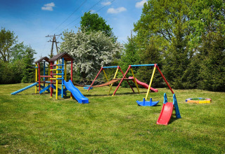 Parque infantil con toboganes, columpios y arenero en césped junto a Cottages ranch by the sea en Dinamarca.