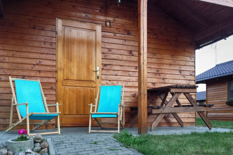 Due sedie a sdraio blu e un tavolo da picnic sulla veranda di una baita a Cottages ranch by the sea in Danimarca.
