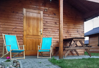 Zwei blaue Liegestühle und ein Holztisch auf der Terrasse einer Hütte bei Cottages ranch by the sea in Dänemark.