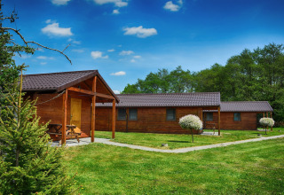 Cabañas de madera en Cottages ranch by the sea en Dinamarca, rodeadas de césped verde y cielo azul.
