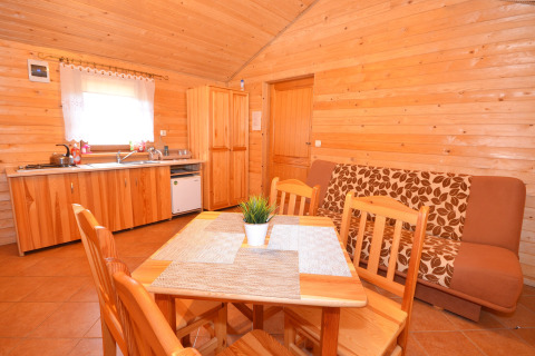 Gemütlicher Innenraum einer Holzhütte mit Küche und Essbereich im Cottages Ranch by the Sea, Dänemark.
