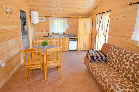 Interior de cabaña acogedora de madera con comedor, sofá, cocina y armario en Cottages ranch by the sea, Dinamarca.