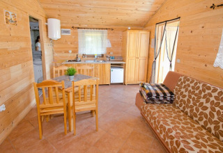Gemütliche Holzhütte mit Esstisch, Sofa, kleiner Küche und Schränken im Cottages ranch by the sea, Dänemark.