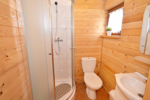 Badeværelse i træ, med bruser, toilet og håndvask, i sommerhus på Cottages ranch by the sea i Danmark.