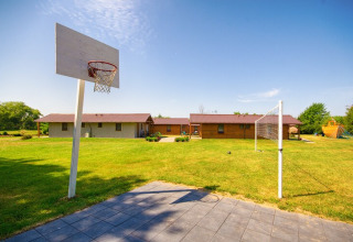 En græsplæne med basketballkurv, volleyballnet og hytter fra Cottages ranch by the sea i Danmark.