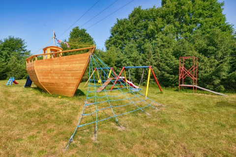 Parque infantil con casa de juegos en forma de barco, red para escalar y columpios en Cottages ranch by the sea, Dinamarca.