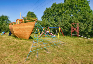Spielplatz mit schiffsförmigem Kletterhaus, Schaukeln und Rutschen bei Cottages ranch by the sea in Dänemark.