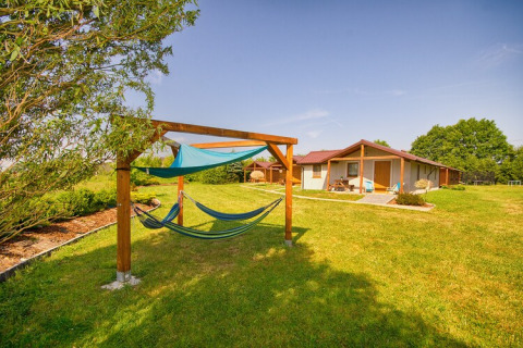 Blick auf grüne Wiese mit Hängematten und gemütlichen Hütten bei 'Cottages ranch by the sea' in Dänemark.
