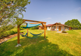 Udsigt over grøn græsplæne med hængekøjer og hyggelige hytter ved 'Cottages ranch by the sea' i Danmark.